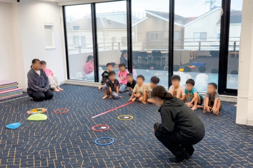職員が子どもと一緒に机を囲み、宿題や活動に取り組んでいる様子
